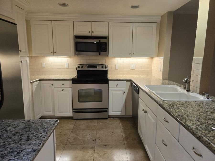 A clean white kitchen with granite counters