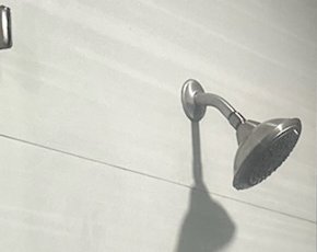 A clean shower head on a light tile wall